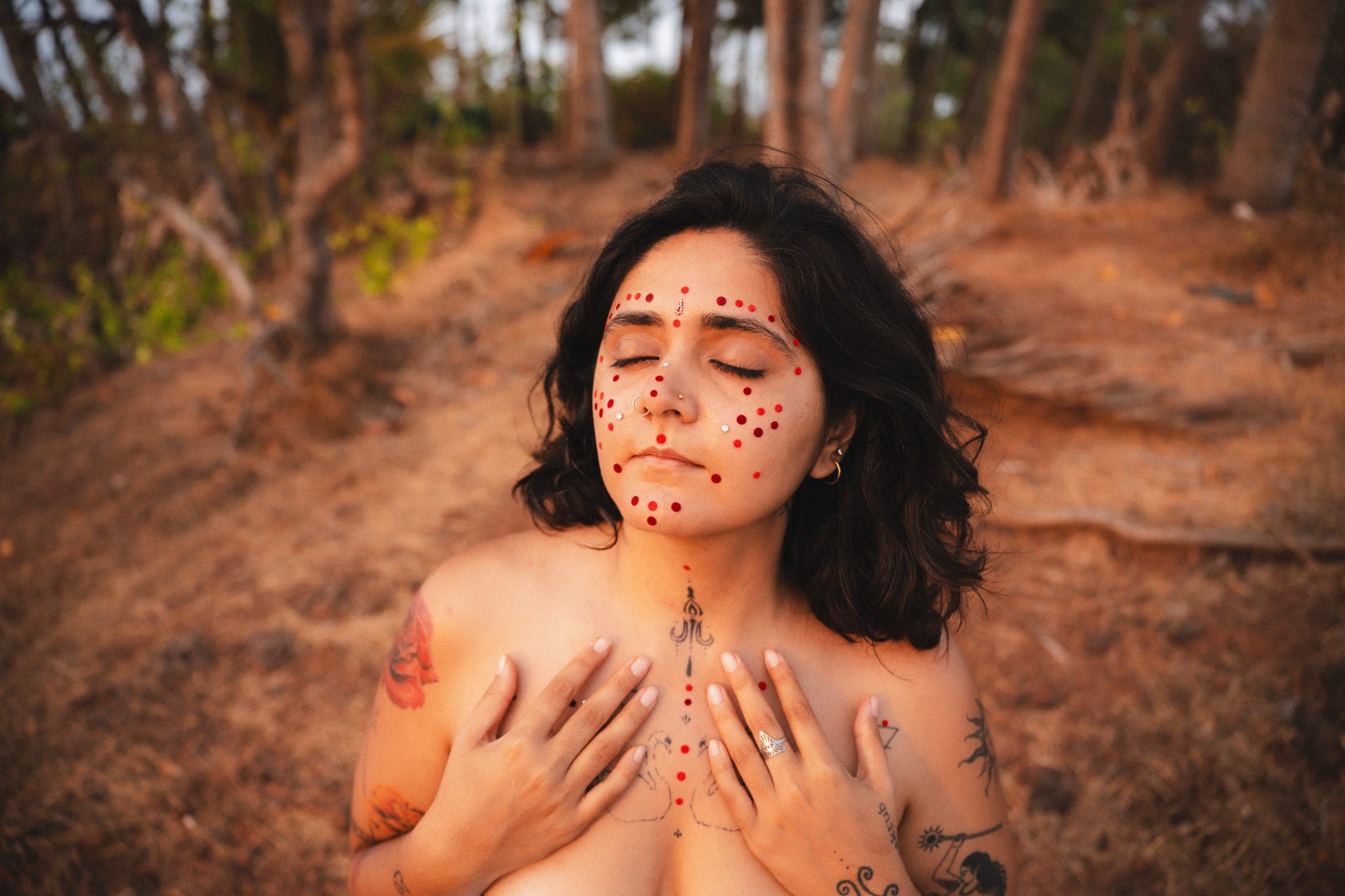 Hansika in a forest with hands resting on her chest